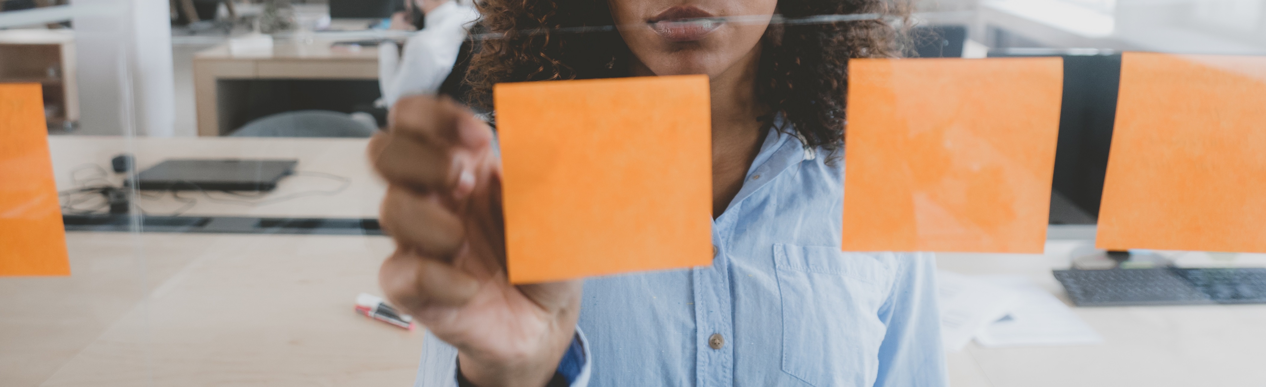 Person sticking orange post-it notes to a window